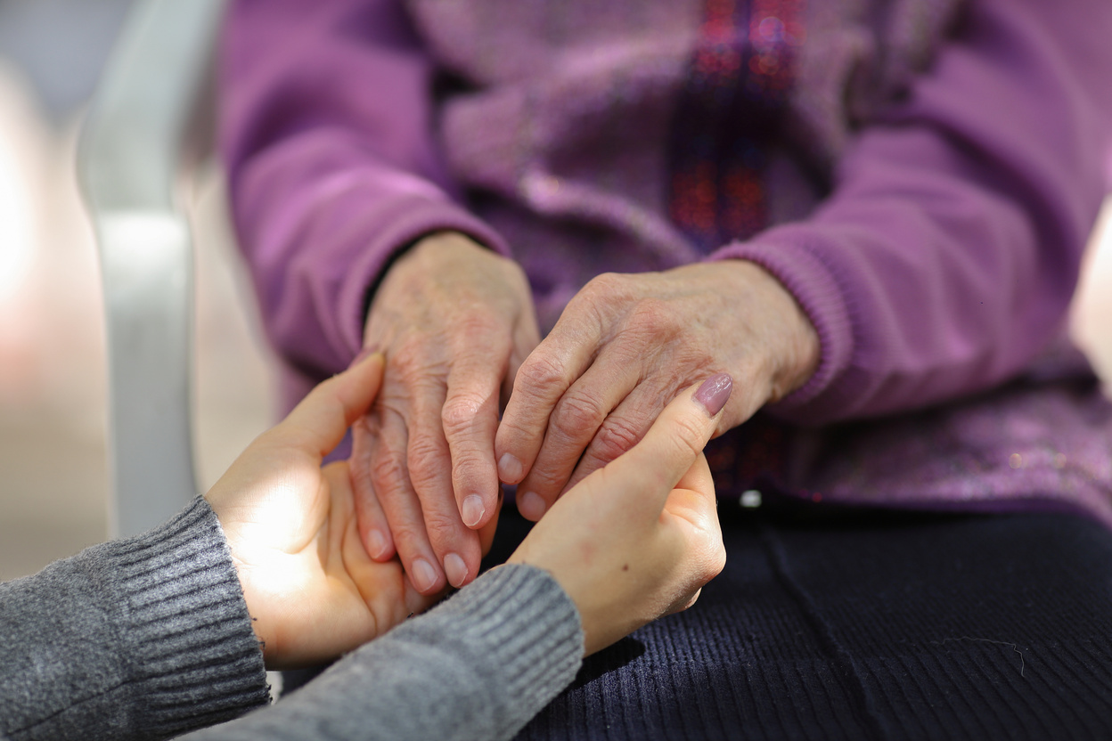 Young caregiver holding seniors hand. Elderly concept